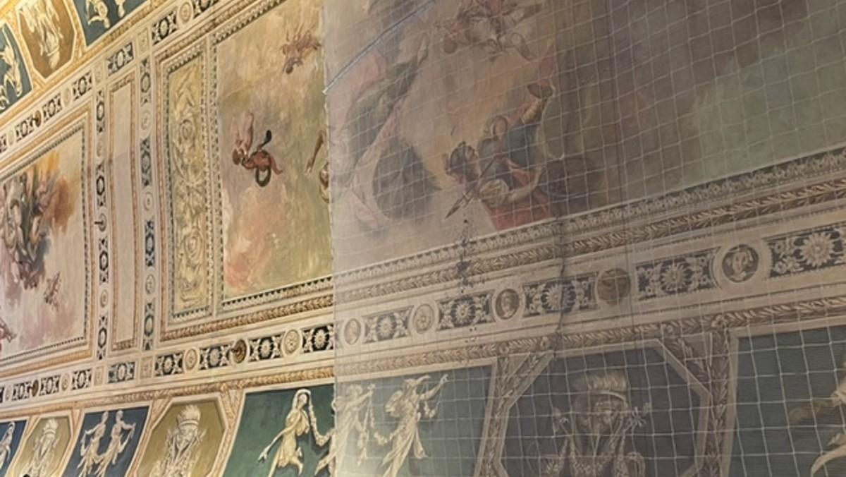 La grieta, protegida con una malla, de los murales de 'El Vigatà' que decoran la biblioteca del Ateneu Barcelonès.