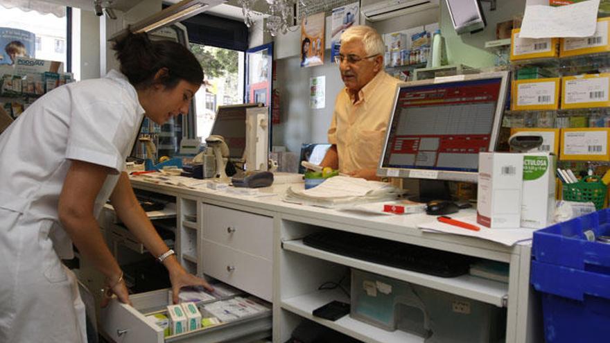 Una farmacéutica atiende a un paciente en su establecimiento.