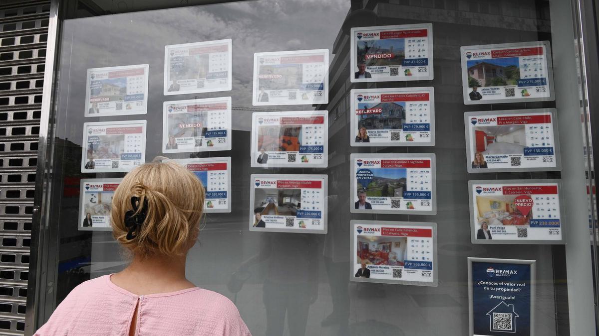 Una mujer observa las ofertas de pisos en una inmobiliaria.
