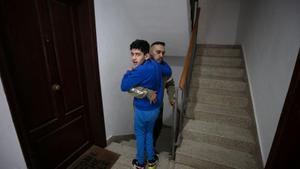 Pese a los intensos dolores que sufre, Arshad Bashir carga a su hijo por la escalera.