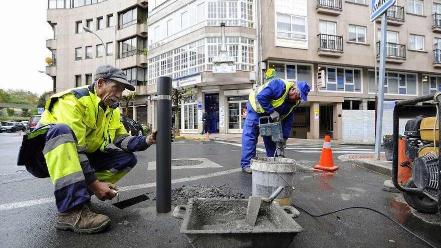 Dos trabajadores colocan pivotes en una plaza de Lalín. // Bernabé/Javier Lalín