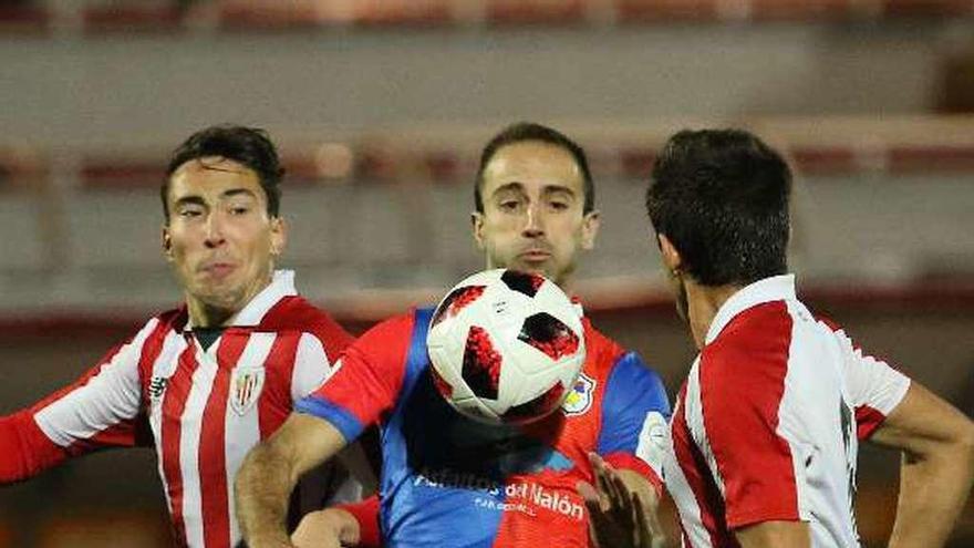 El jugador del Langreo Aimar lucha con dos rivales en Lezama.