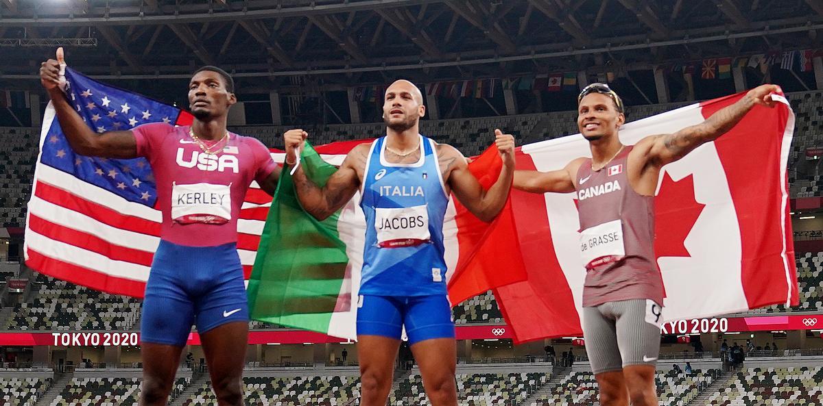 Lamont Marcell Jacobs, de Italia, celebra el oro junto a Fred Kerley, de Estados Unidos, y Andre De Grasse, de Canadá.