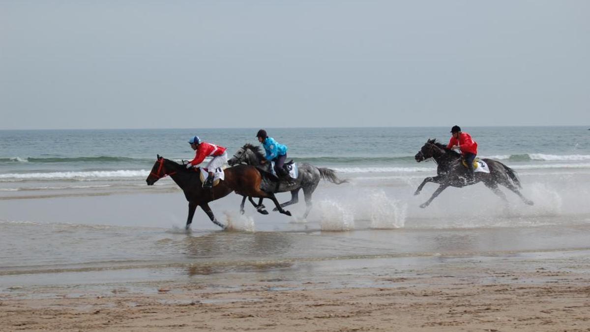 Varios jinetes en una edición anterior de las carrera de caballos en la playa de Santa Marina.