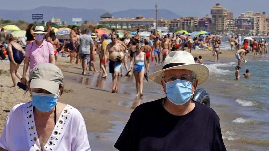 Dos personas pasean por la orilla de la playa de La Patacona.