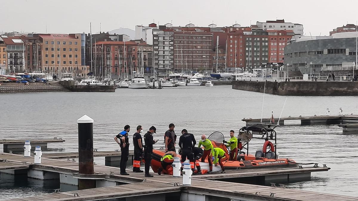 Bomberos y policías, tras recuperar el cadáver, ayer, en el puerto deportivo.