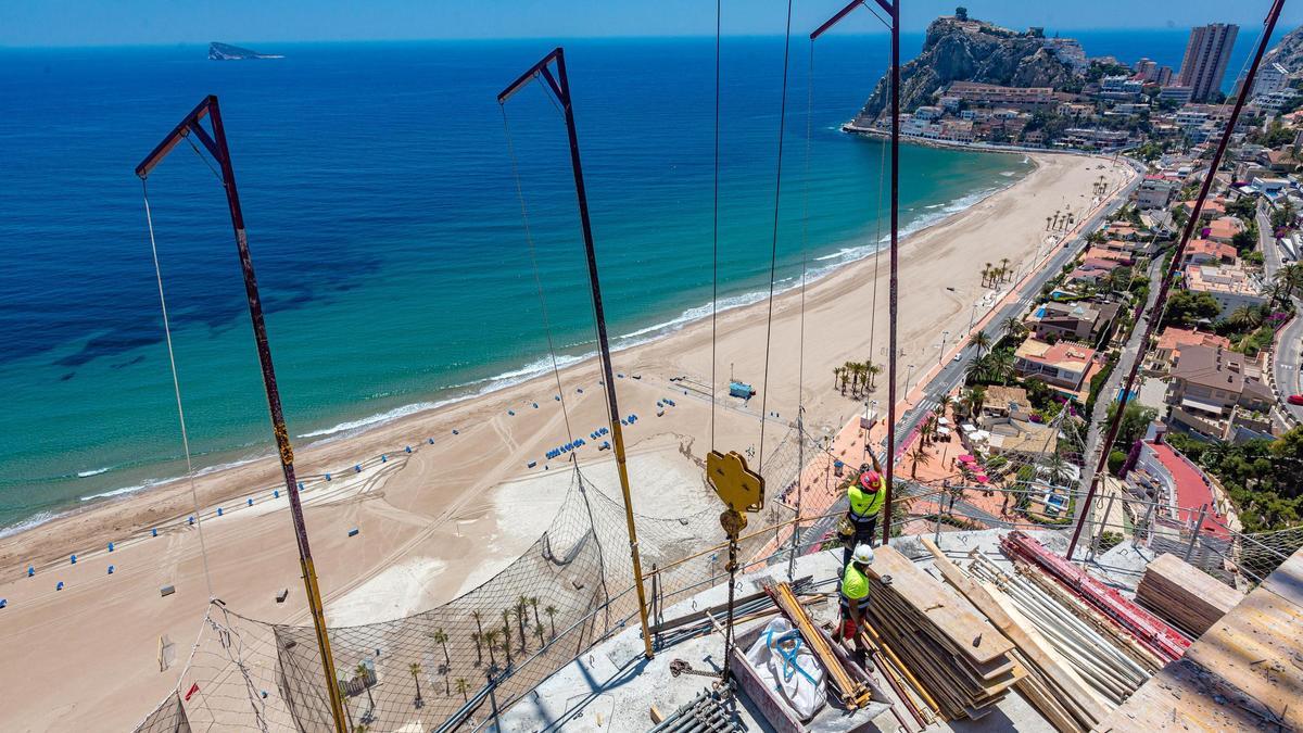 Operarios de la construcción trabajando en la cubierta de un edificio en primera línea del mar.