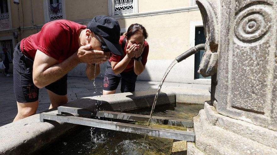 Dos personas se refrescan en la histórica Fonte dos Tornos de Pontevedra.