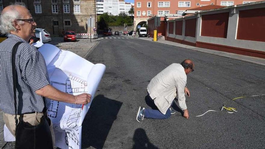 Un hombre sostiene los planos mientras otro mide para pintar el espacio de la antigua prisión.