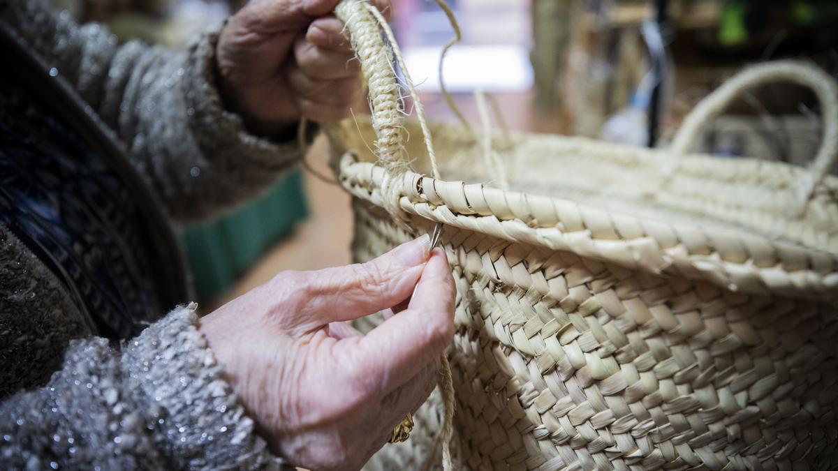 Las manos expertas de Antonia arreglan el asa de un bolso.