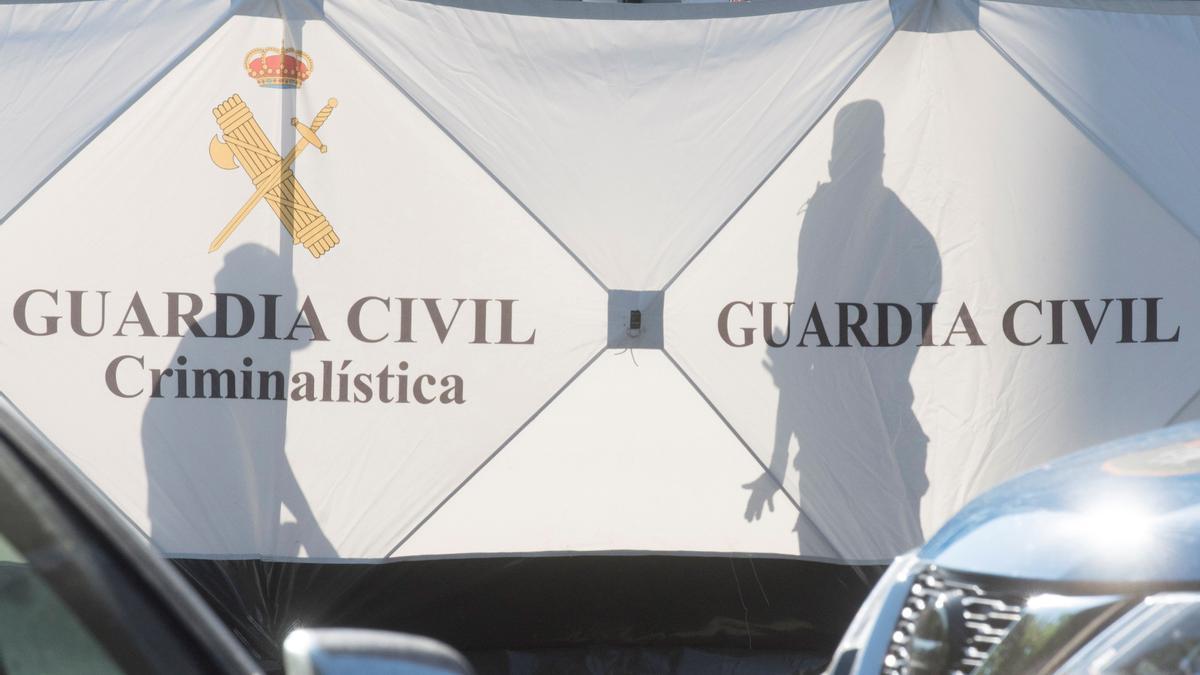 Miembros de la Guardia Civil tras la lona para tapar la escena del crimen.