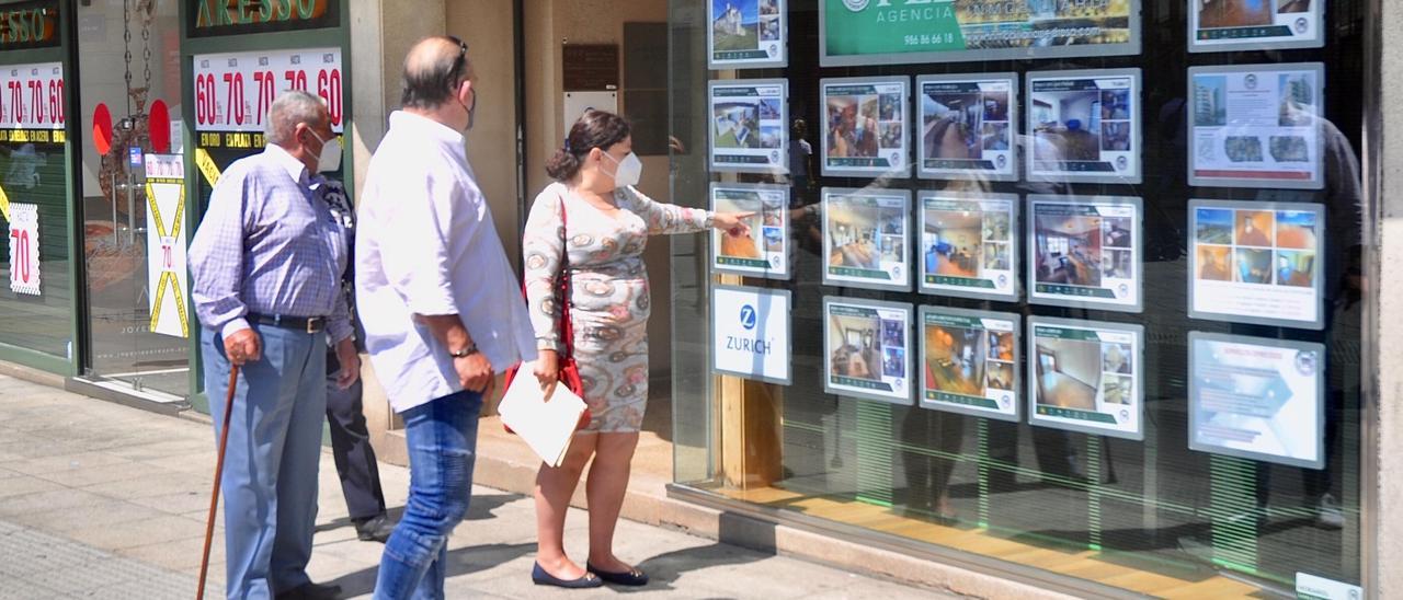 Varios ciudadanos ante el escaparate de una inmobiliaria