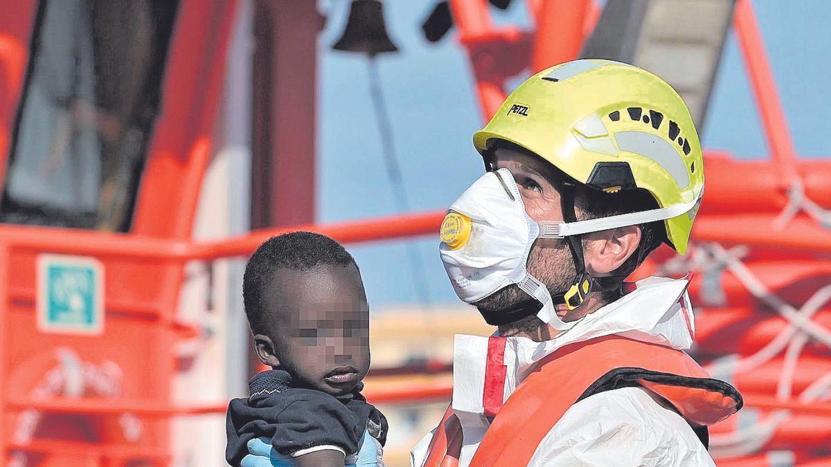 Un miembro de Salvamento Marí­timo, con un niño llegado en cayuco al puerto de La Restinga, en El Hierro, Canarias.