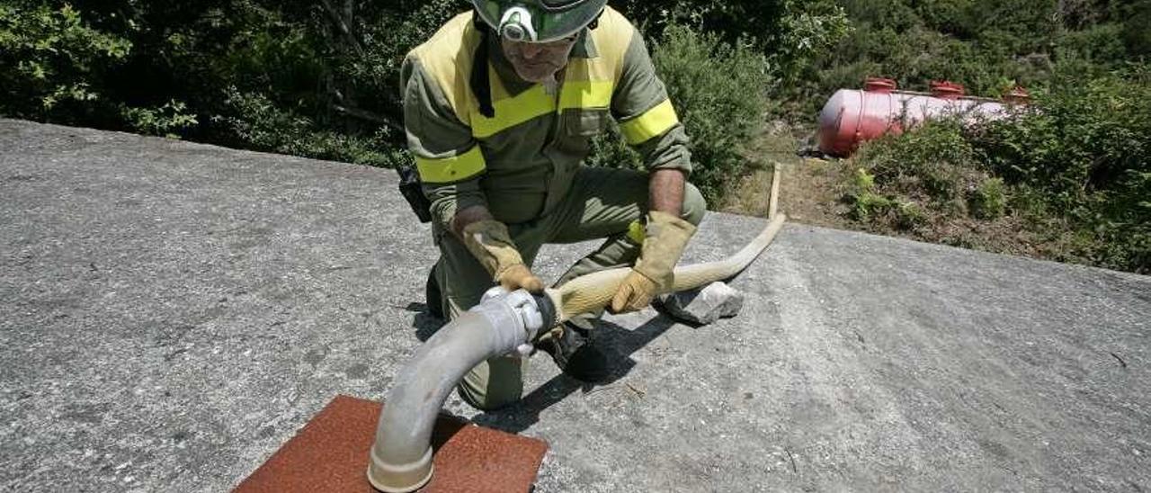 Personal municipal de Emerxencias, ayer, vertiendo una cisterna de agua en el depósito. // Bernabé / Cris M.V.