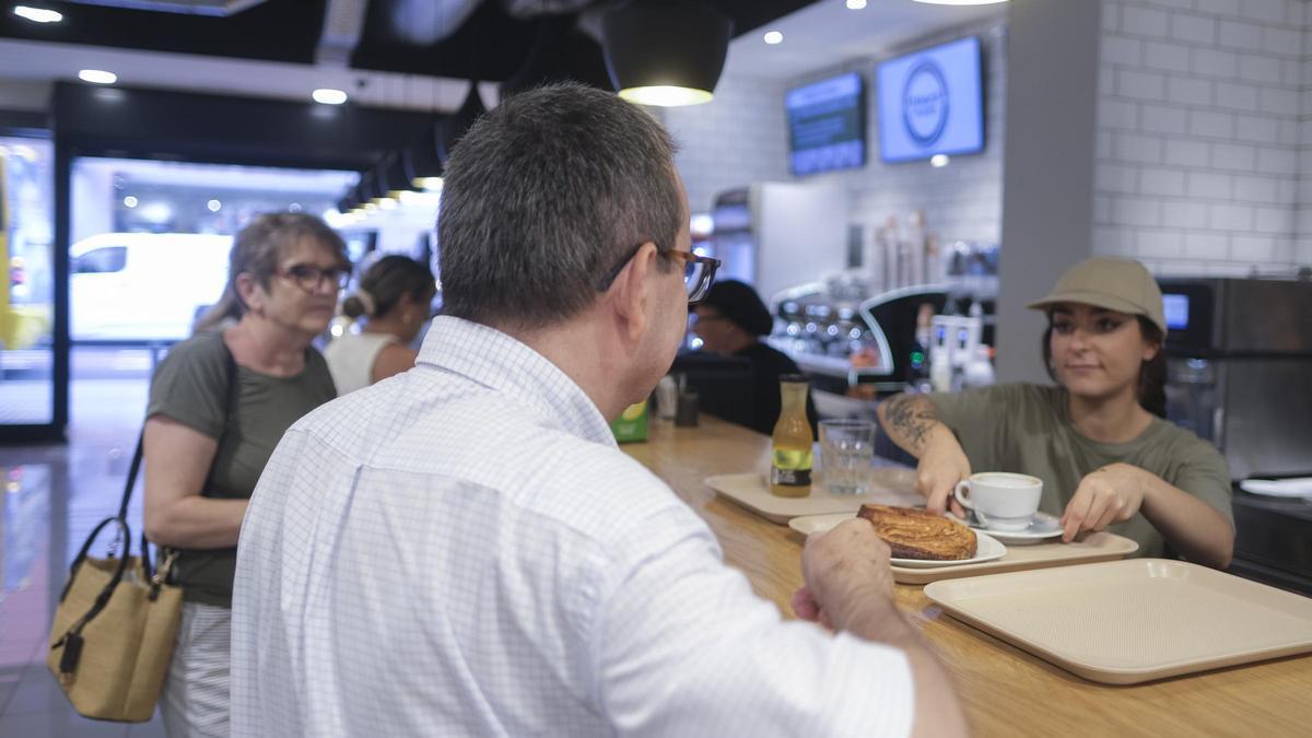 Varias personas desayunan en una cafetería.