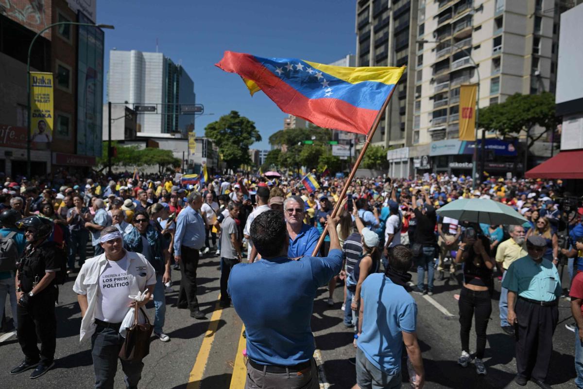 A demonstrator waves a Venezuelan flag during a protest called by the opposition on the eve of the presidential inauguration in Caracas on January 9, 2025. Venezuela is on tenterhooks facing demonstrations called by both the opposition and government supporters a day before President Nicolas Maduro is due to be sworn in for a third consecutive term and despite multiple countries recognizing opposition rival Edmundo Gonzalez Urrutia as the legitimate president-elect following elections past July. (Photo by JUAN BARRETO / AFP)