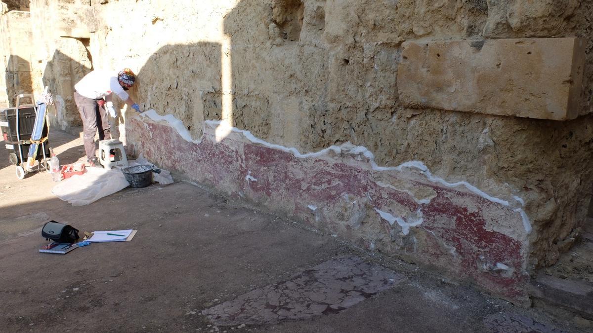 Un operario trabaja sobre el revestimiento de un mural en Medina Azahara.