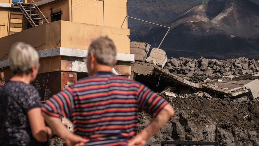 Dos vecinos de La Laguna (Los Llanos de Aridane) contemplan el volcán y los destrozos provocados por la colada. | | ANDRÉS GUTIÉRREZ