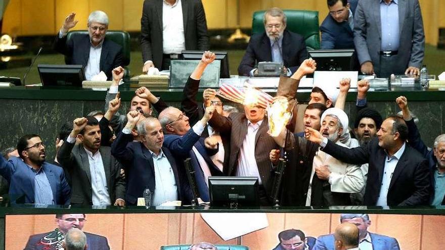 Un grupo de diputados iraníes quema una bandera de papel de EE UU en el Parlamento.