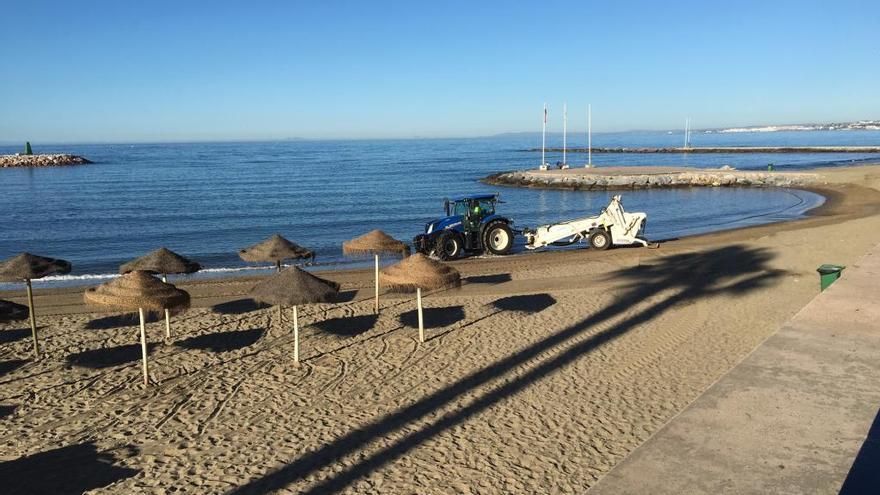 Un tractor limpia la arena de la playa de El Faro, una de las tres de Marbella que conserva la distinción.