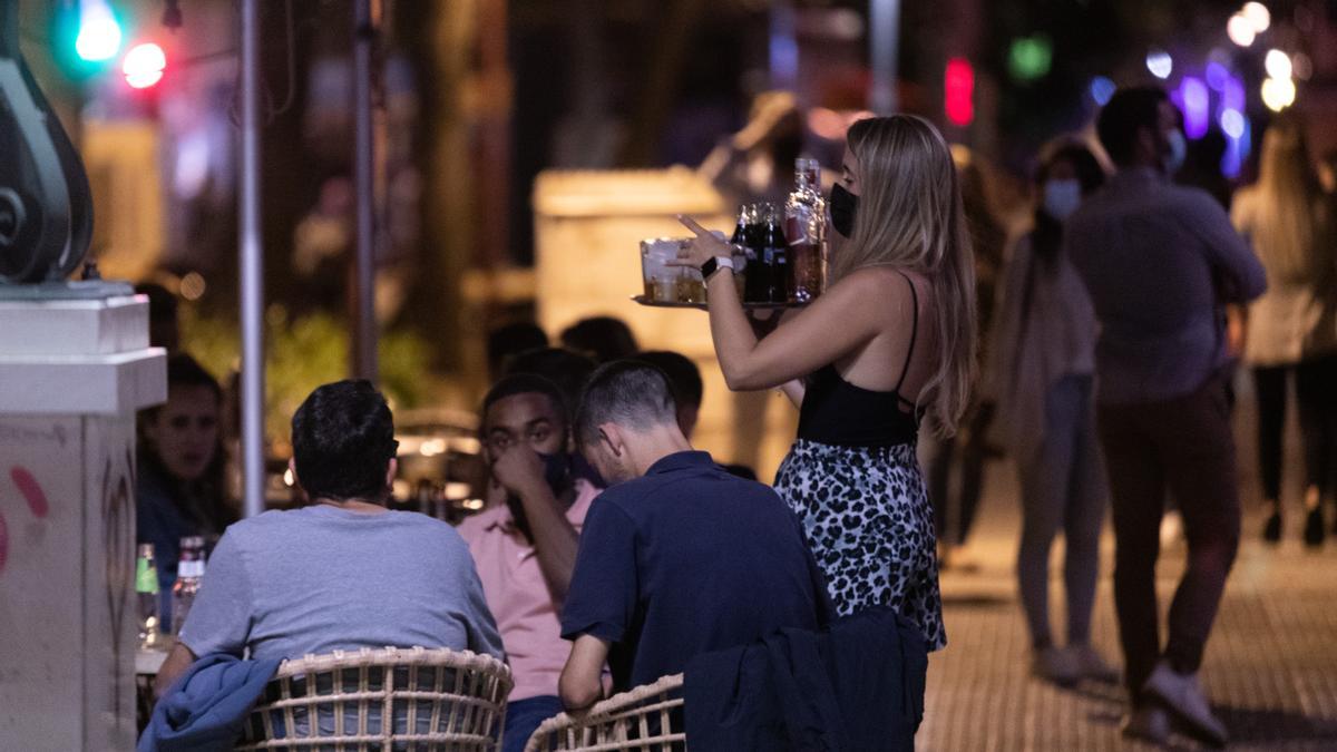 Una camarera atiende a varias personas en la terraza de un bar