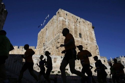 Athletes are silhouetted as they participate in the fourth international Jerusalem marathon, in Jerusalem's Old City