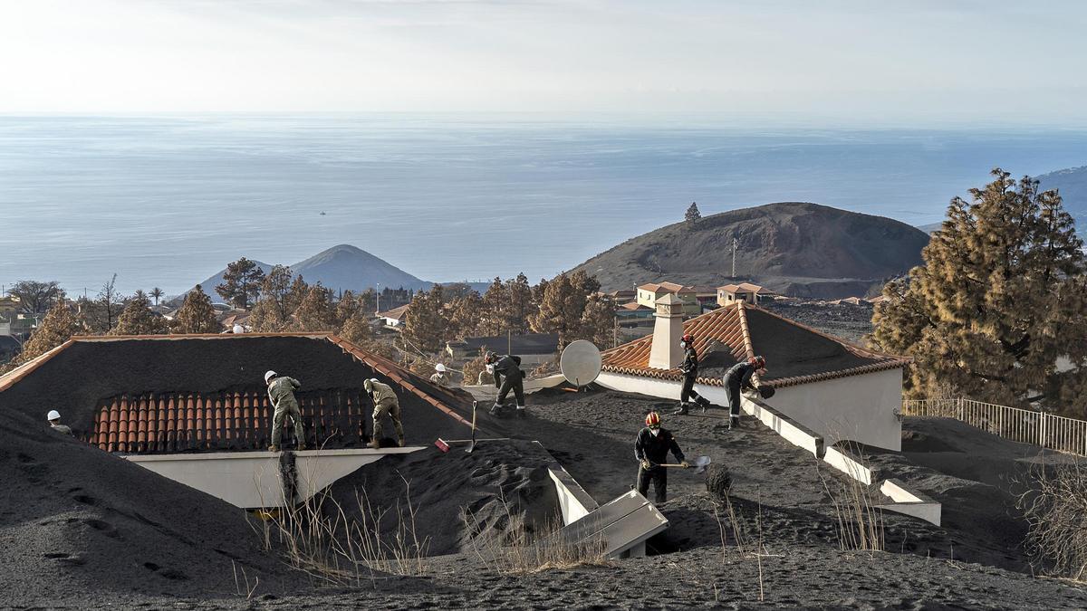 Operarios retirando la lava acumulada en los tejados de las casas.