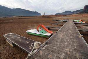 Esta fotografía tomada el 15 de enero de 2024 muestra un antiguo muelle y barcos en suelo seco junto al embalse de bajo nivel de Sau, con al fondo la iglesia de Sant Roma de Sau, en la provincia de Girona en Cataluña. Cataluña lucha contra una sequía histórica desde hace tres años y algunos residentes ya experimentan restricciones de agua en su vida diaria.