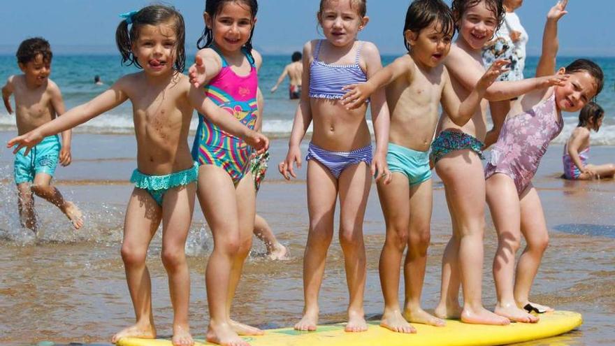 Seis alumnos del colegio de las Dominicas, ayer, sobre una tabla de surf en San Lorenzo.