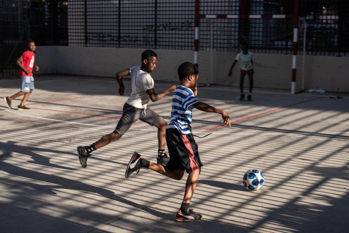 Niños inmigrantes e hijos de inmigrantes, y vecinos del barrio del Remei de Vic juegan a fútbol en un parque.