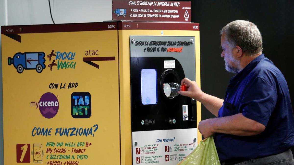 Un hombre tira una botella de plástico en un punto de reciclaje en Roma.