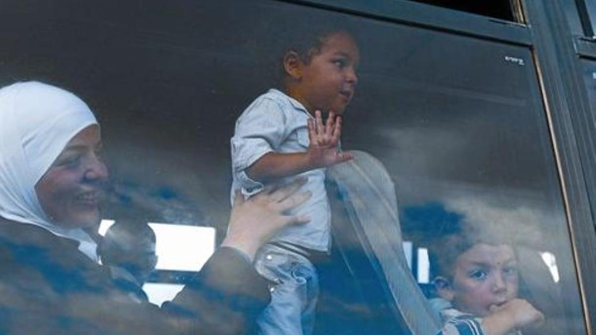 Unos niños inmigrantes saludan desde un autocar que los traslada en Lampedusa.