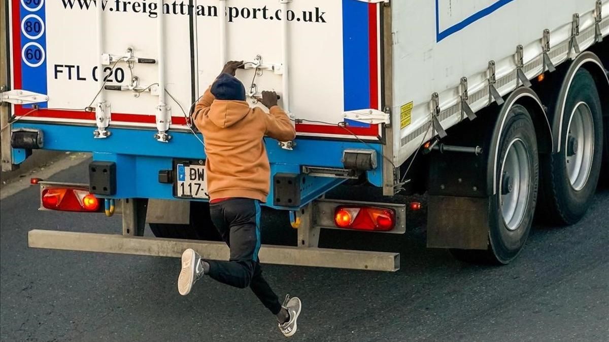 Un inmigrante trata de aferrarse a un camión que se dirige a un ferry en la ciudad francesa de Ouistreham con la esperanza de llegar al Reino Unido.