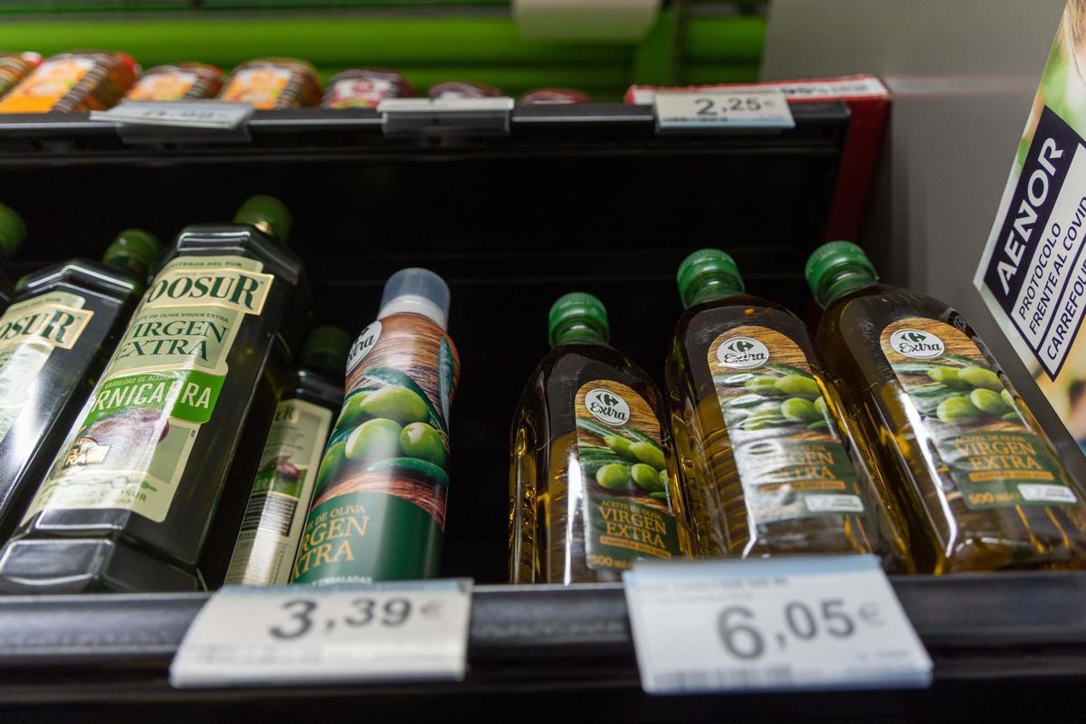 Un estante de un supermercado lleno de botellas de aceite de oliva