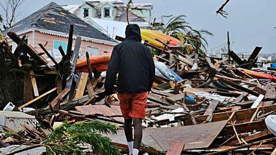 Un home camina entre les restes d&#039;una casa a les Bahames.