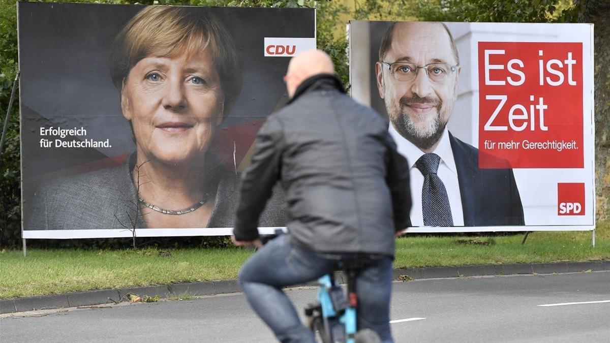 Un ciclista pasa frente a dos carteles electorales de Merkel (izquierda) y Schulz, en Essen, el 14 de septiembre.