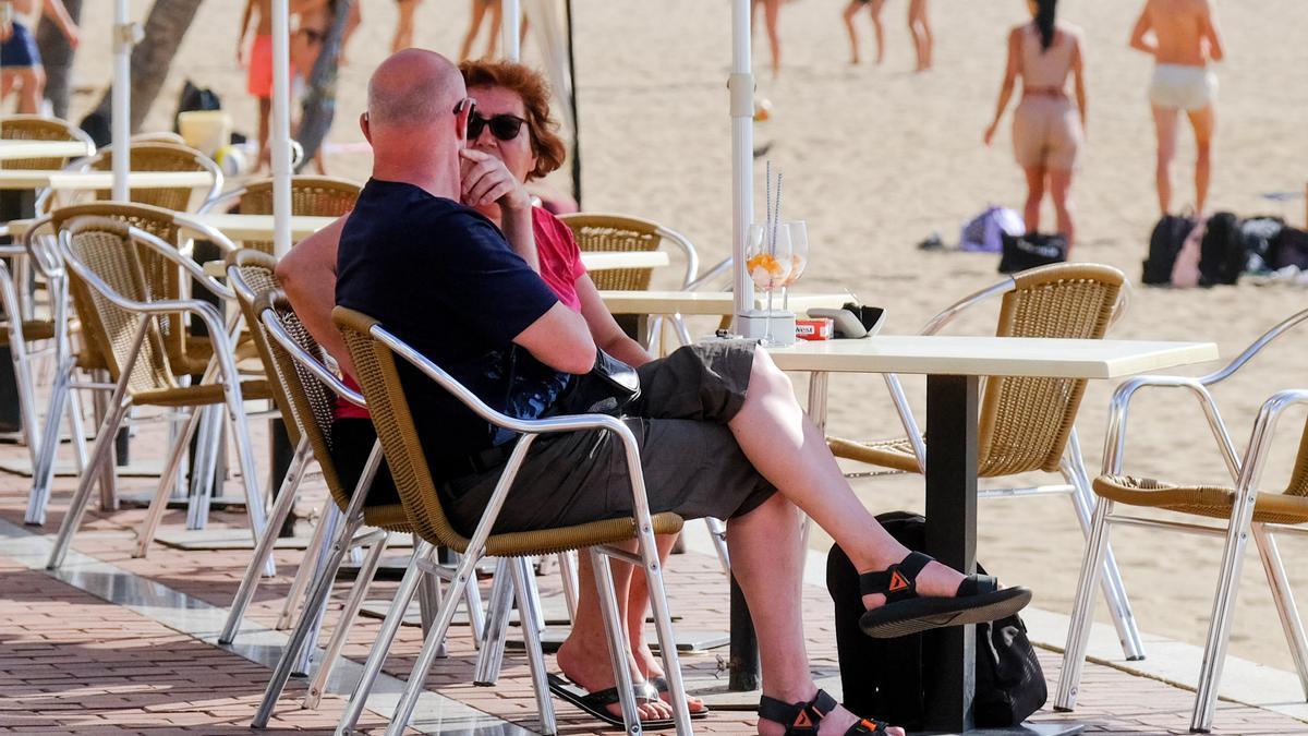 Una pareja de turistas toma algo en una terraza.