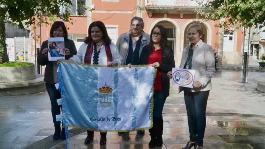 Carmen Santos y Silvia Carballo sostienen la bandera de Bueu, hoy, con alfombristas de la asociación. | Gonzalo Núñez