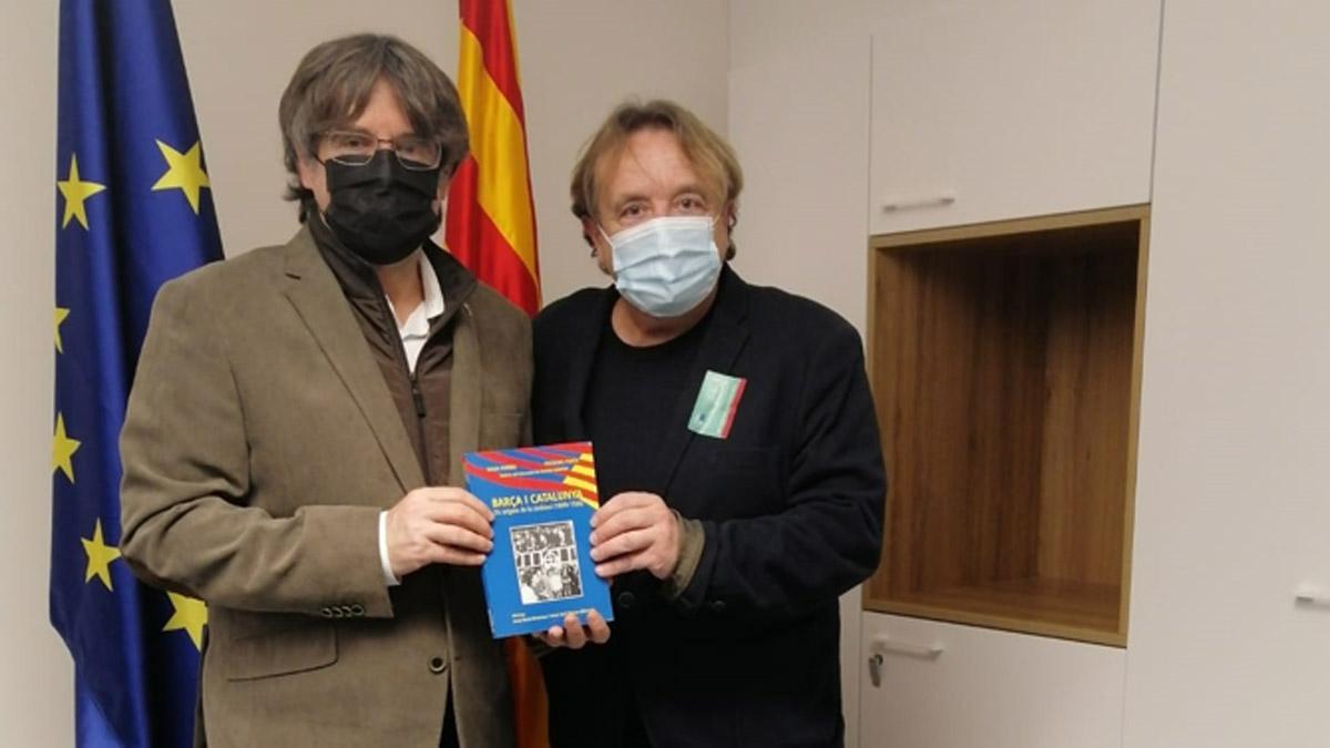 Carles Puigdemont recibe el libro de la conferencia de manos de Salva Torres