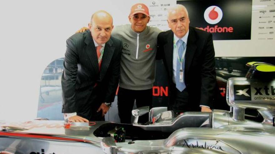 Taller. Diego Torrico, directivo de Vodafone, Luciano Alonso y Lewis Hamilton posan con uno de los coches de McLaren.