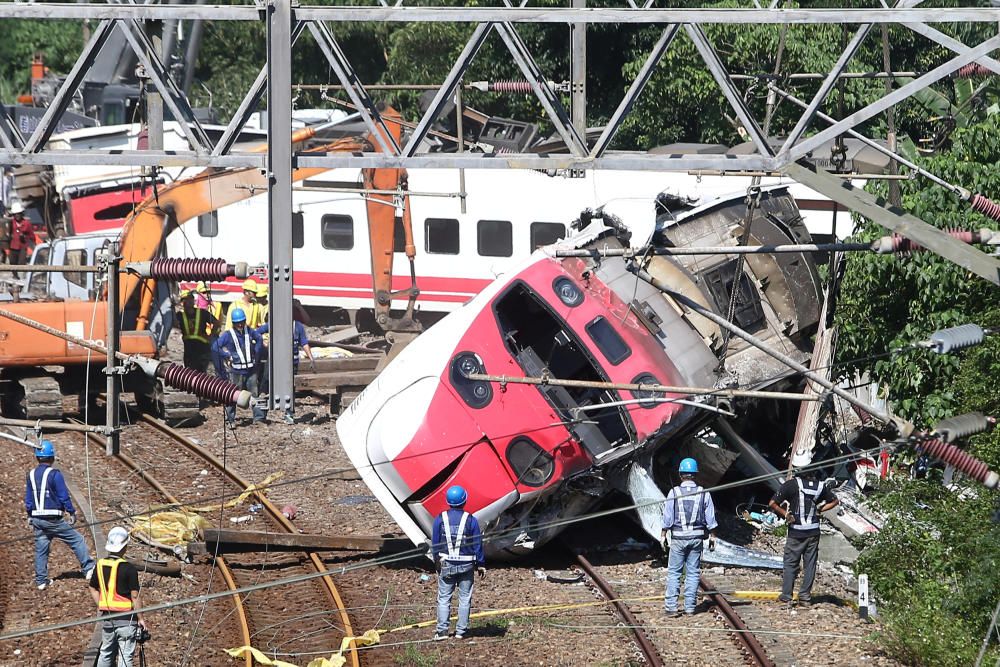 Rescue workers work at the site where a train ...