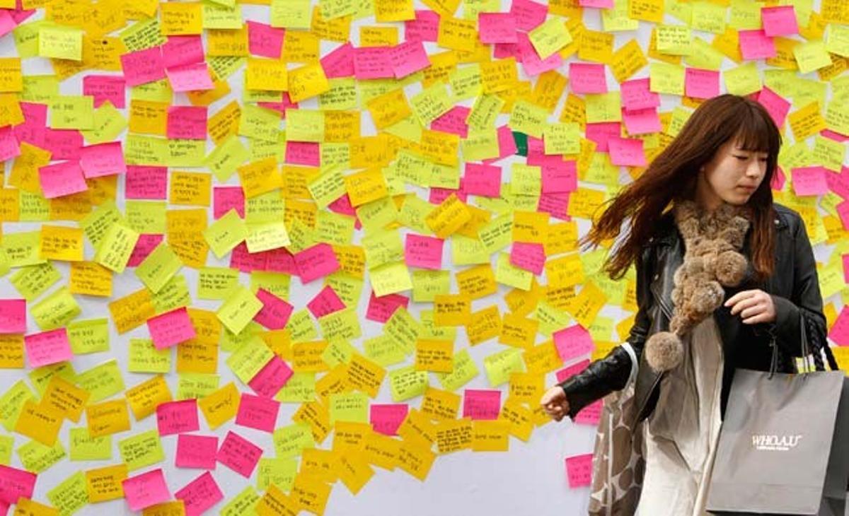 Una dona passa davant un mur cobert de missatges de solidaritat després d’escriure una nota per a les víctimes del terratrèmol i el tsunami del Japó, a Seül, Corea del Sud.