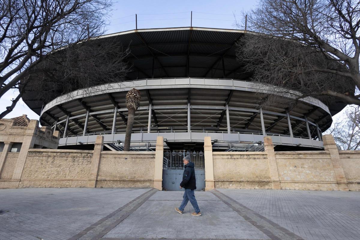 Un hombre pasa por delante de la Plaza de Toros de Xàtiva.