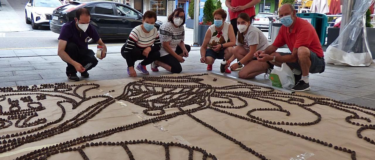 Por la izquierda, agachados, Tomás Menéndez, Maribel García, Susana García, Fina Rodríguez, Elisa Alonso y Javier Menéndez, y, de pie, Yolanda Rodríguez, trabajando en la decoración de la alfombra en Tineo. | D. A.