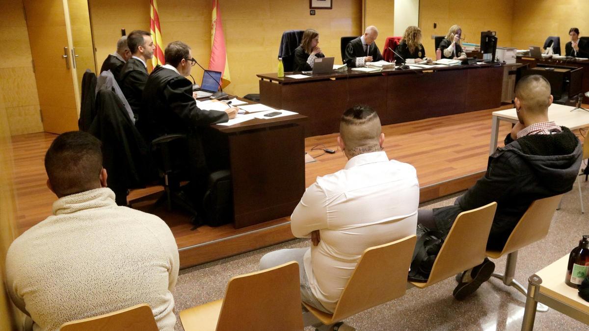 D'esquenes, els tres acusats d'apunyalar un jove per motius racistes a Santa Coloma de Farners. Foto del judici a l'Audiència de Girona
