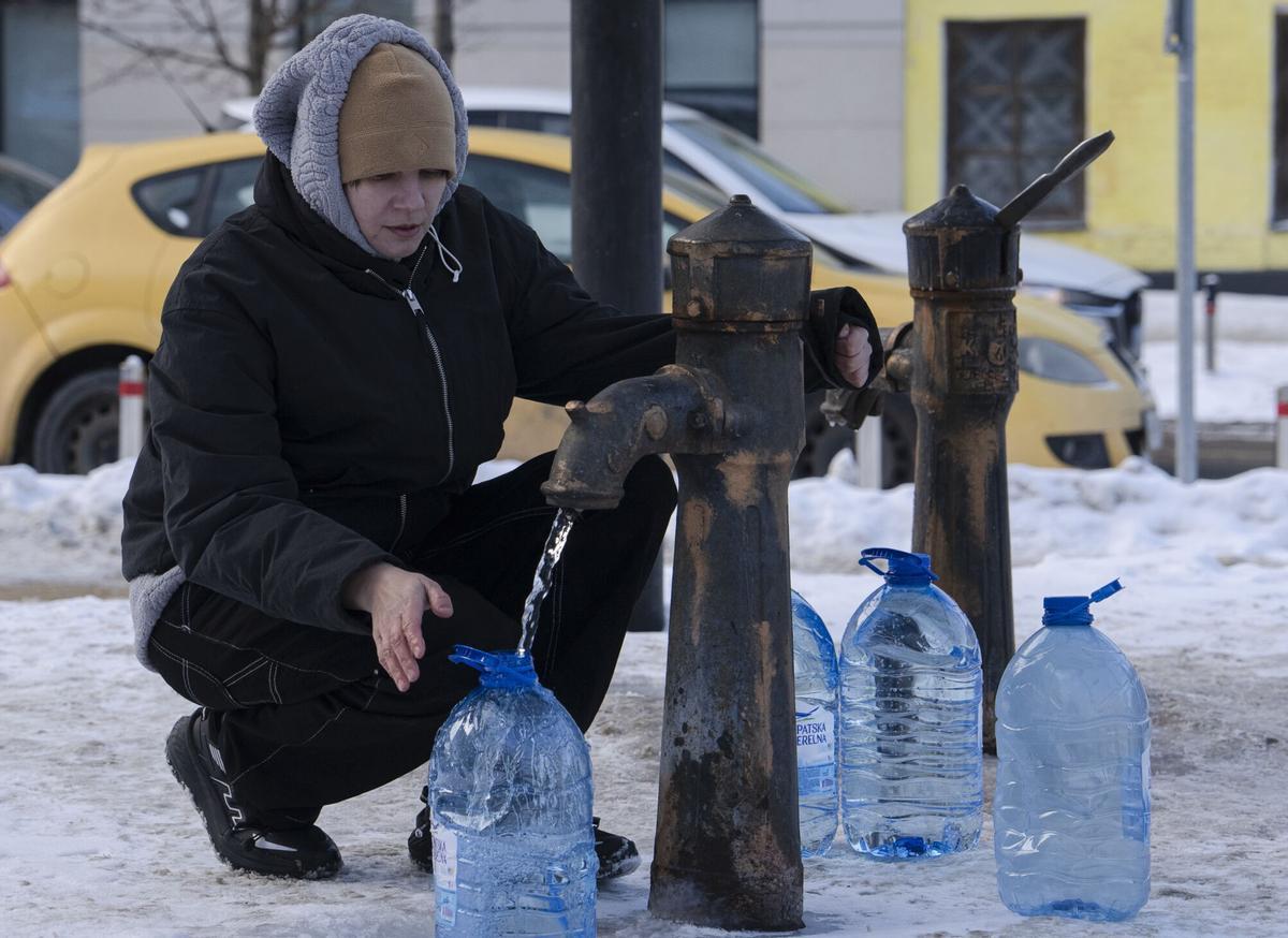 Una mujer llena garrafas de agua en una fuente pública de Kiev.