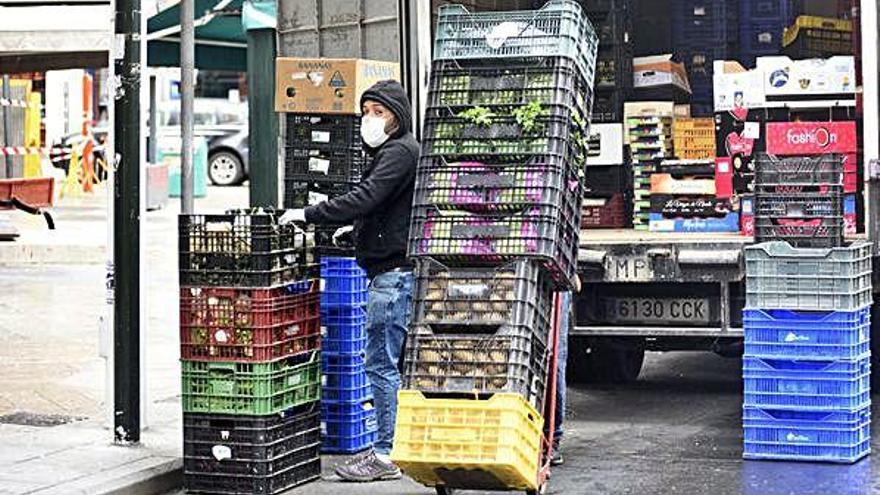 Un trabajador descarga varios palés de verduras en el centro de Murcia.