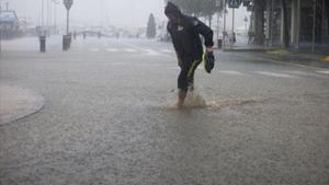 Un transeünt travessa un carrer inundat a l’Ampolla, al Baix Ebre.