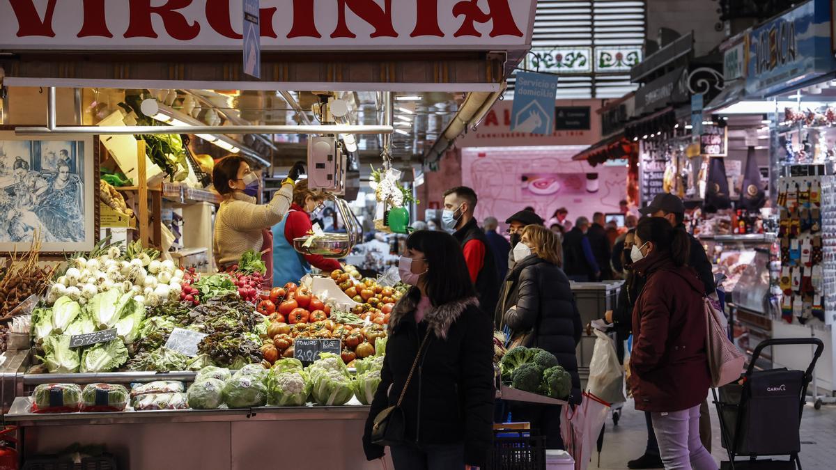 Archivo - Varias personas compran en un puesto de fruta y verdura en un mercado.