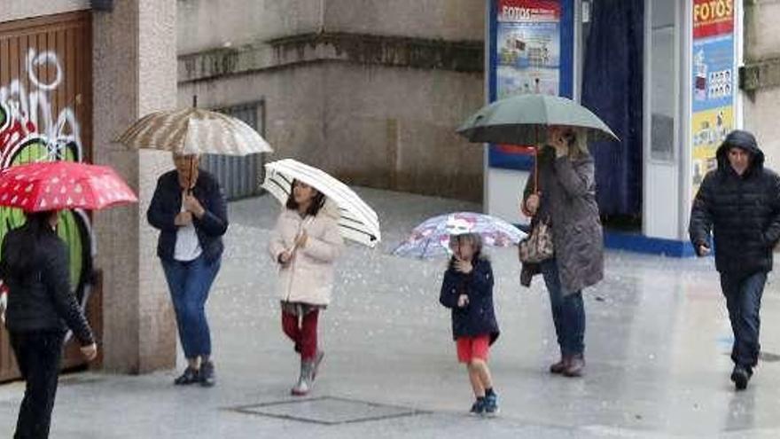 Varios transeúntes se protegen de la lluvia, ayer, en Vigo. // J. Lores